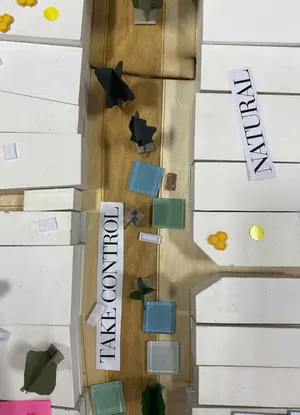 Looking to be the centrepiece of our exhibition, we proposed to create a site model of Dudley Highstreet at 1:200 scale with buildings modelled in a simple form. Local residents and visitors to the exhibition are then invited to decorate a chosen building to how they would envision it sat within the context of a greener Highstreet. We want to tie in our themes of biodiversity and materials by proposing that buildings can, and do, have the potential to be a lot healthier, sustainable, and interactive on the street. This site model also helps gain vital public opinions on the Highstreet and prompts discussion of areas most in need of attention.

To ensure that the model is utilising the MDF to the most efficient standard possible. First, the centres of the massing blocks have been hollowed out. This allows a reduction in materials used as other buildings can be cut in the centres of the model. Then the top is finished with a solid piece.
The waste material is placed into the recycling rack where other students can reuse it; otherwise, if the material left cannot be used for another project, it is recycled correctly by the university.

The model spanned just over 3.4m long and over 50cm wide. With the majority being cut from scrap woods that would fit the jigsaw of the shape, we were able to drastically cut down on waste. We also got some small benches and bee hives printed from recycled plastics, and used dried flowers as trees to represent the green spaces. Ultimately, the model seemed like a huge success, and really helped portray our ideas about Dudley High Street to those who came by. Everyone from Dudley who saw the model knew that it was the High Street, and interacted well with it. The size did make it difficult to move, especially to carry to the site, but it sat nicely in the centre of the the room and really drew people in to interact with it.

The model brought people in from outside to play with, write on, interact with. It became a spectacle for the public to come in and see what was happening and offer their ideas about what could be done.

The event was a success. Many people from the public (those who heard about the event, and those who just happened across it on the day) came in to interact with the model, which sat as the centre piece in the room. Kids liked to play with the pieces while the adults talked about things that could come from actions to help the High Street, not just leave it as is.

SOME OF THE KEY IDEAS WERE:
- The Shops need to be inviting for everyone. It’s no good having these places to go if people would rather take a bus to the next town.
- Just putting up boards across the windows is awful. Paint, Posters, Graffiti: Anything that actually makes the High Street look still alive is better than just wooden boards.
- More Green is needed. While it is obvious that there is a lack of Trees, many people wanted to push for these small bushes or planting spaces that could easily be implemented across the street.
- Spaces for public events or for people to at least gather at. While there is the Market and Fountain, it is not enough for the people of Dudley.
- Something needs to be done about the cars on the High Street. Some were Pro-Removal of all Cars, while some just wanted to limit when they could access the High Street.

Following the exhibition we created a series of drawings with our own interpretation of Sarah Wigglesworth ‘The Dining Table’ drawing. The drawings are a perfect representation of the our interactive model at the ERA Environmental Exhibition and Event. Showing the interaction the public had with the model, as well as the conversations that were held around the model. - Table 7.png